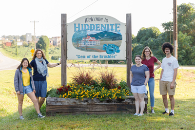 Sharpe Chair and students at Welcome to Hiddenite sign