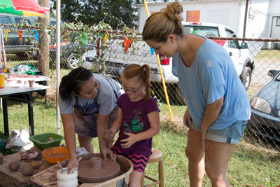 Appalachian State students and young public school student at pottery wheel